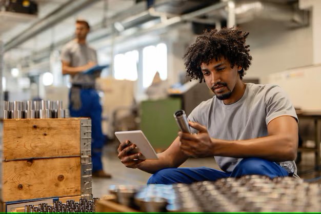 african-american-manual-worker-using-touchpad-while-examining-manufactured-stainless-steel-rods-factory_637285-4062